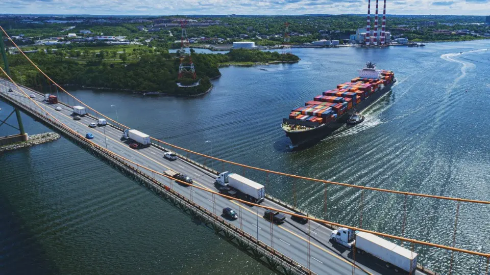 Aerial view of a container ship about to navigate beneath a suspension bridge.