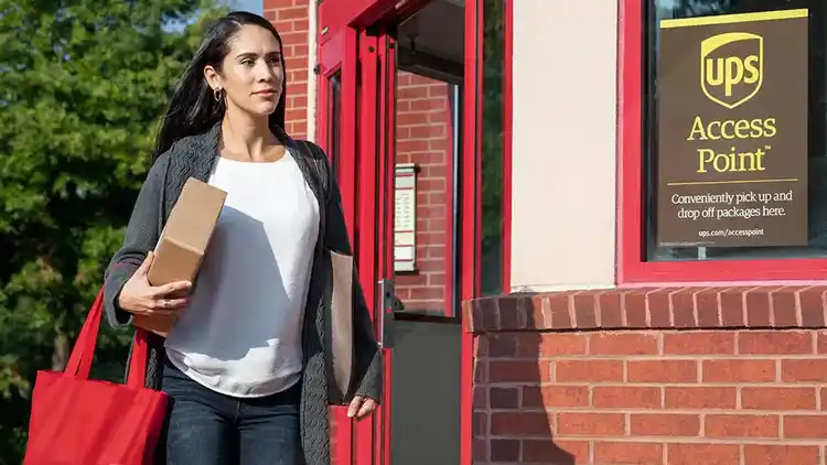 A woman leaving a UPS Access Point with a package.