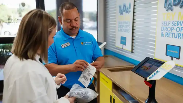 Un empleado en una U-P-S Store asistiendo a un cliente.