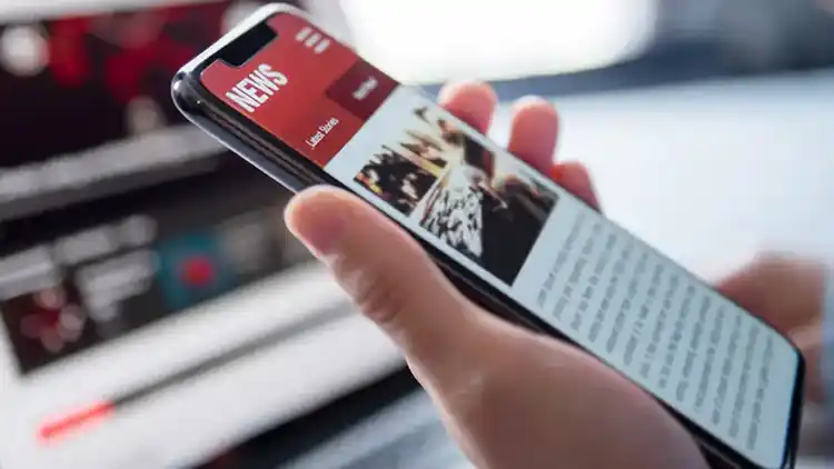 Una persona que utiliza su teléfono inteligente para leer un artículo de noticias.